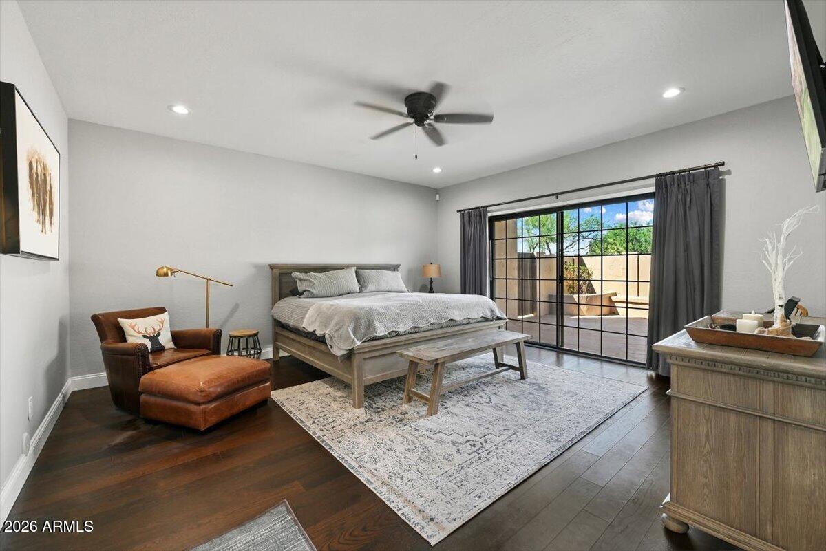 Furnished bedroom with a wood bed and leather chair, opening through sliding glass doors to a patio.