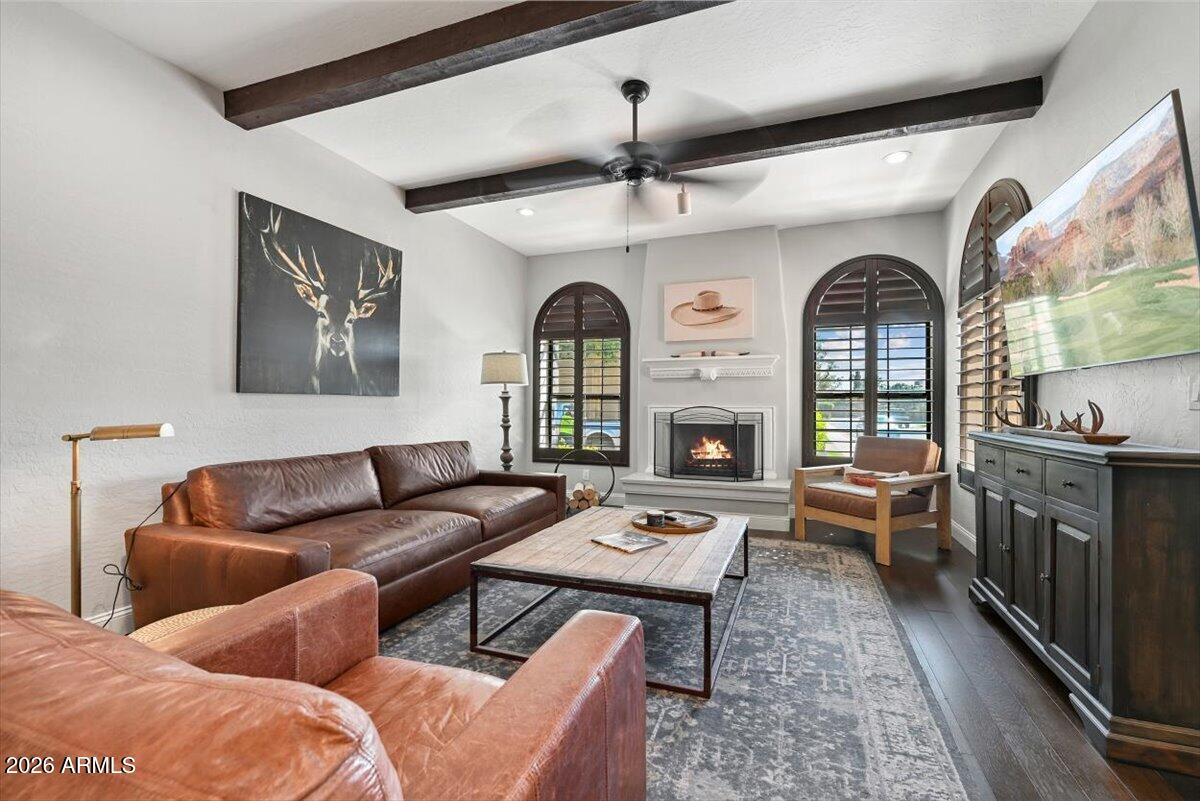 Living room with leather sofas, a fireplace, and arched shuttered windows.