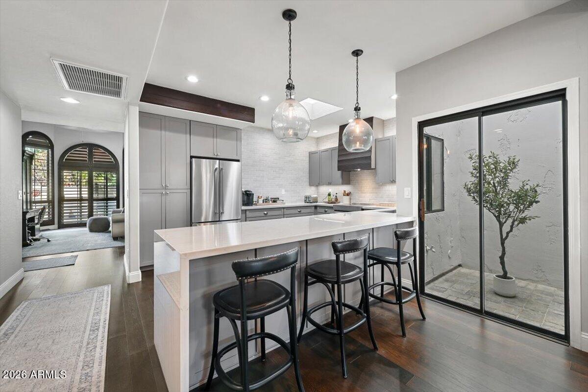 Renovated kitchen with a white island and black stools beside sliding glass doors to a courtyard.