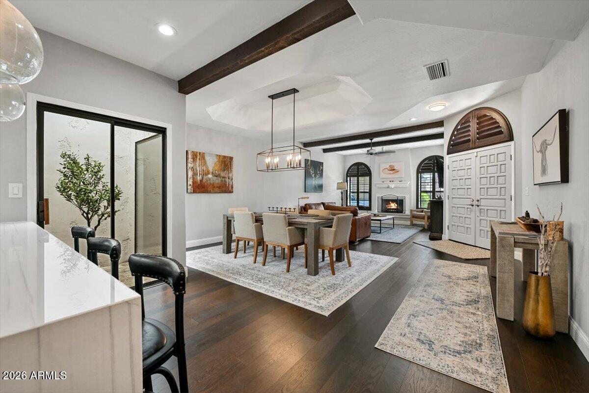 Open-plan living and dining area with a vaulted beamed ceiling and fireplace.