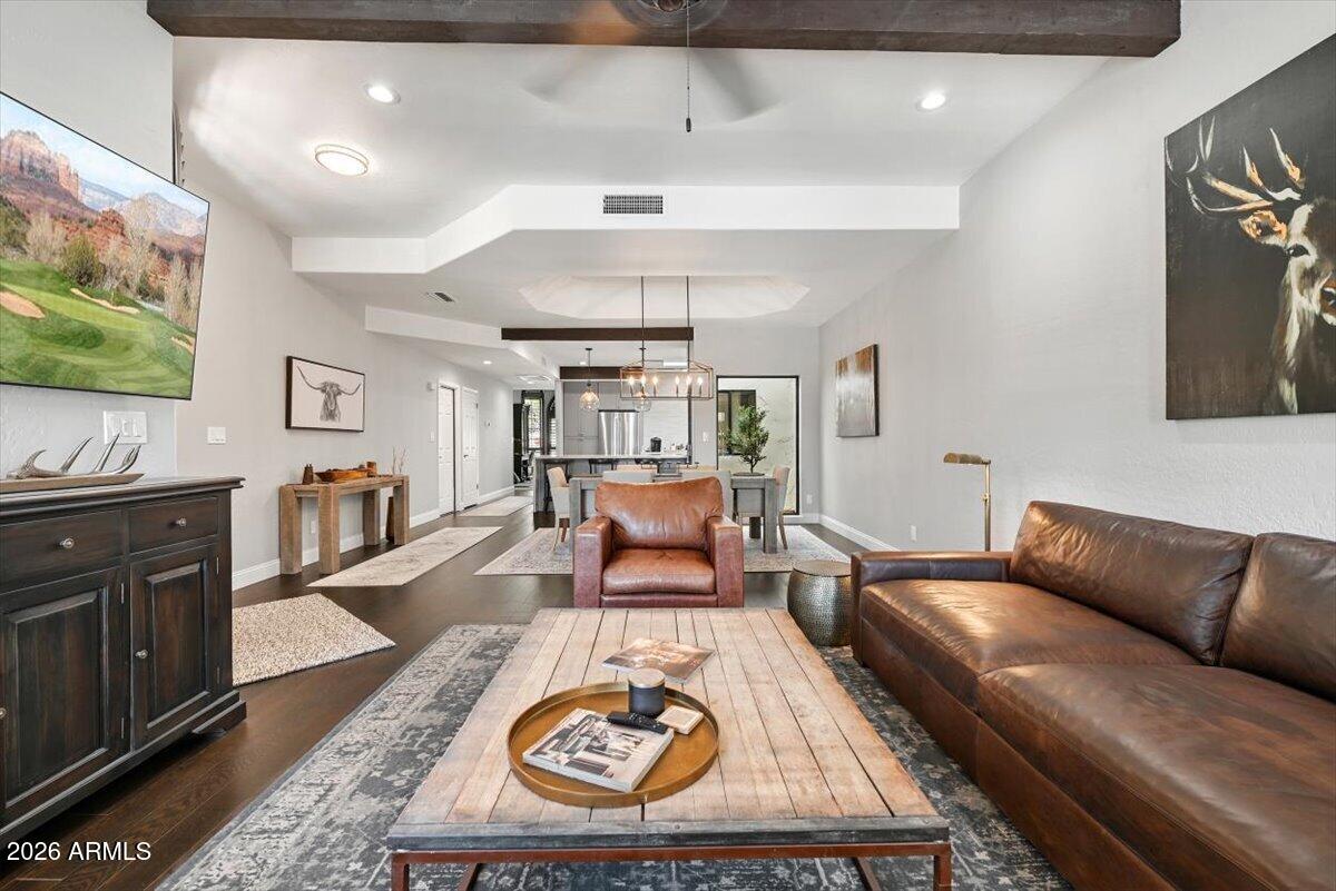 Open-concept living room with leather seating, a wood coffee table, and dining area leading to the kitchen.