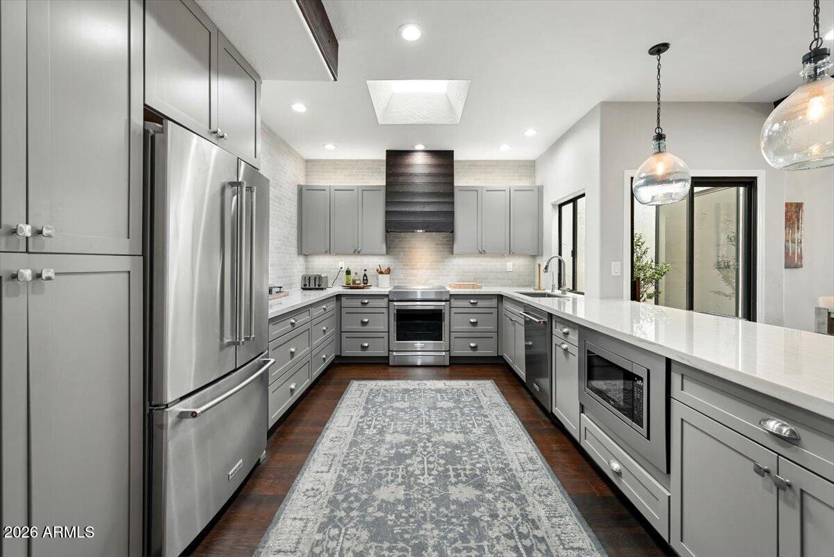 Modern kitchen with gray cabinets, stainless steel appliances, and a long island with a built-in microwave.