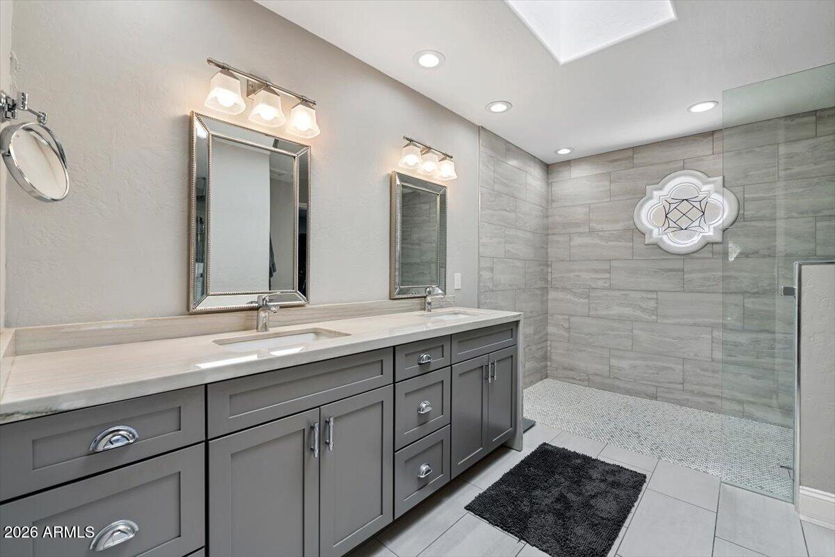 Bathroom with a gray double-sink vanity and spacious gray-tile walk-in shower.