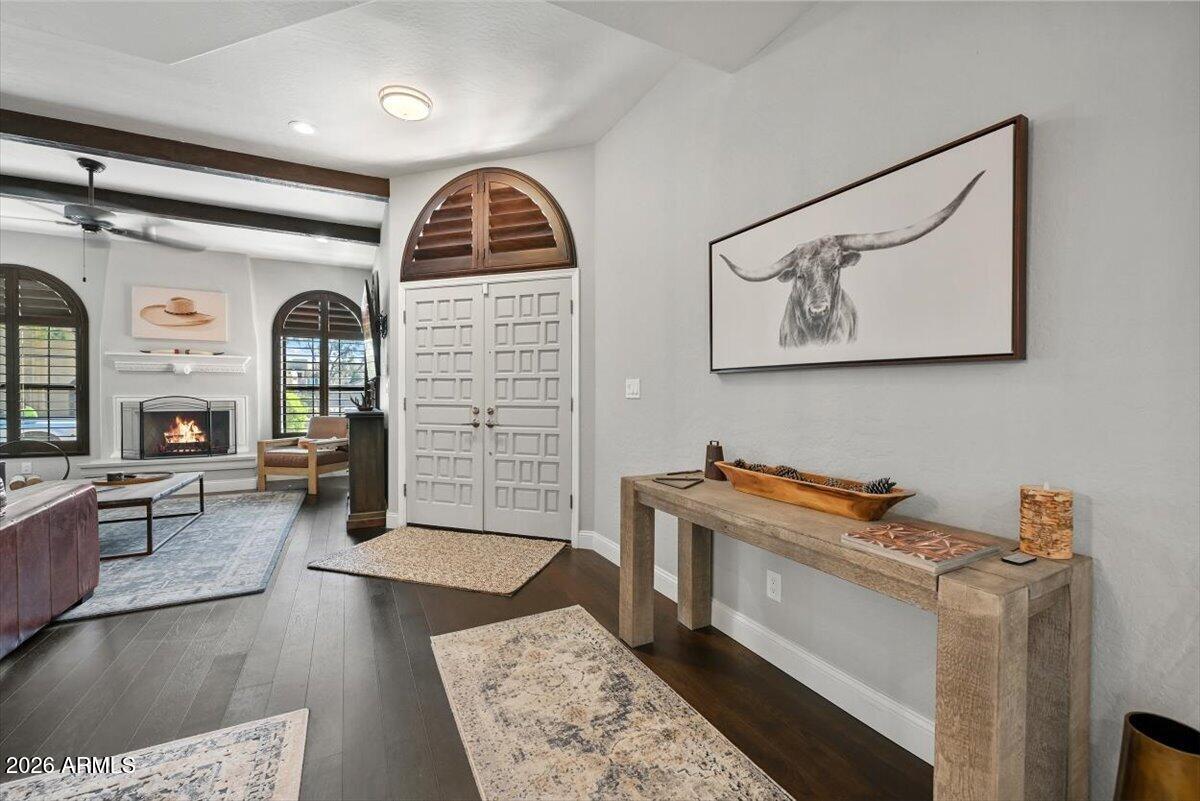 Entryway with arched double doors, a console table, and a living room fireplace beyond.