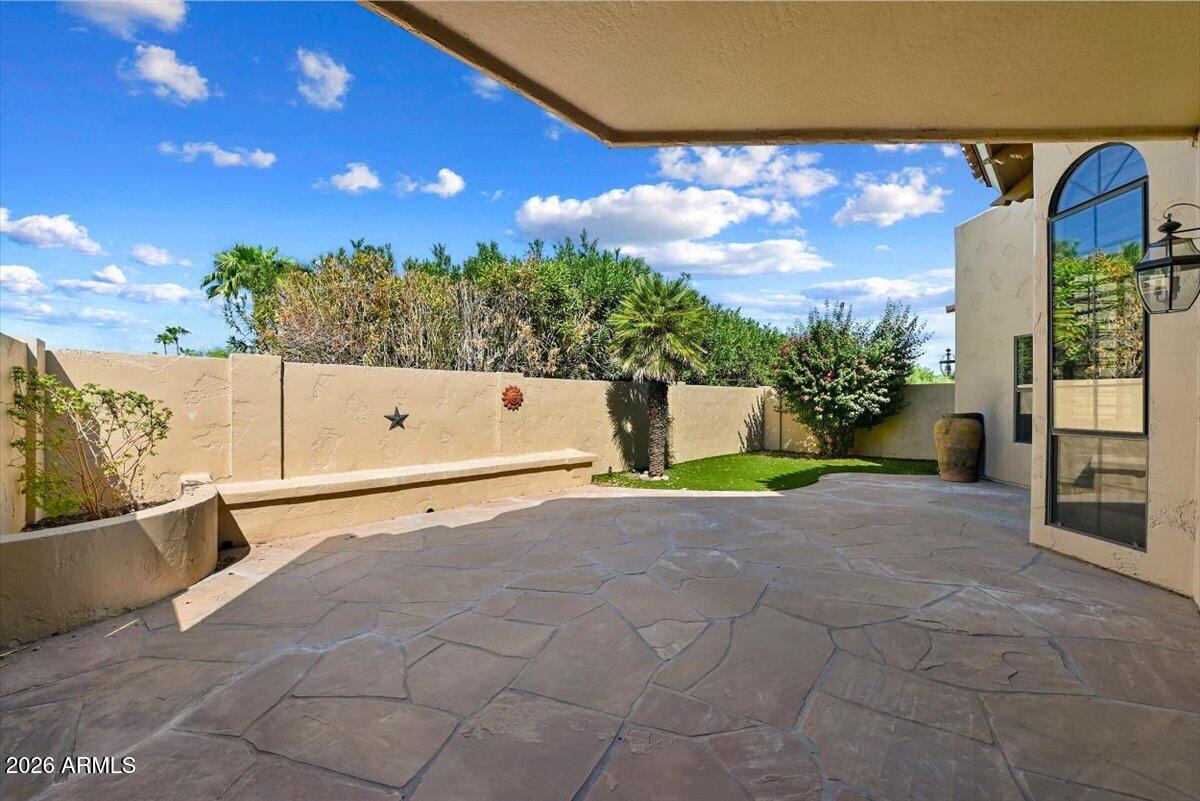 Private flagstone patio with a covered overhang, palm trees, and a small lawn.
