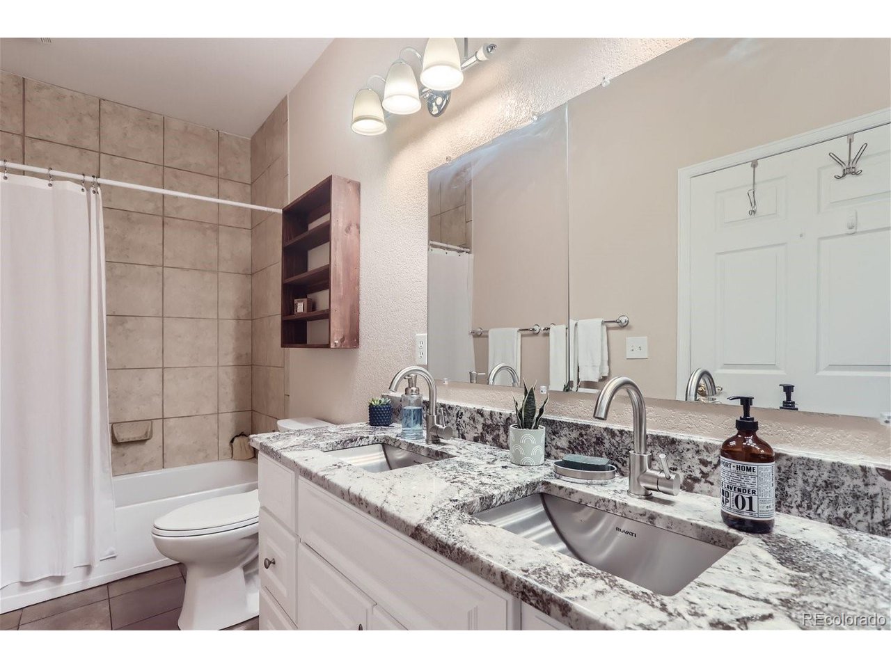 Bathroom with a double-sink stone vanity and tiled tub-shower.