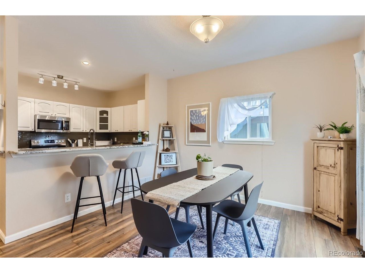 Kitchen and dining area with a breakfast bar, white cabinets, and a dark dining table.