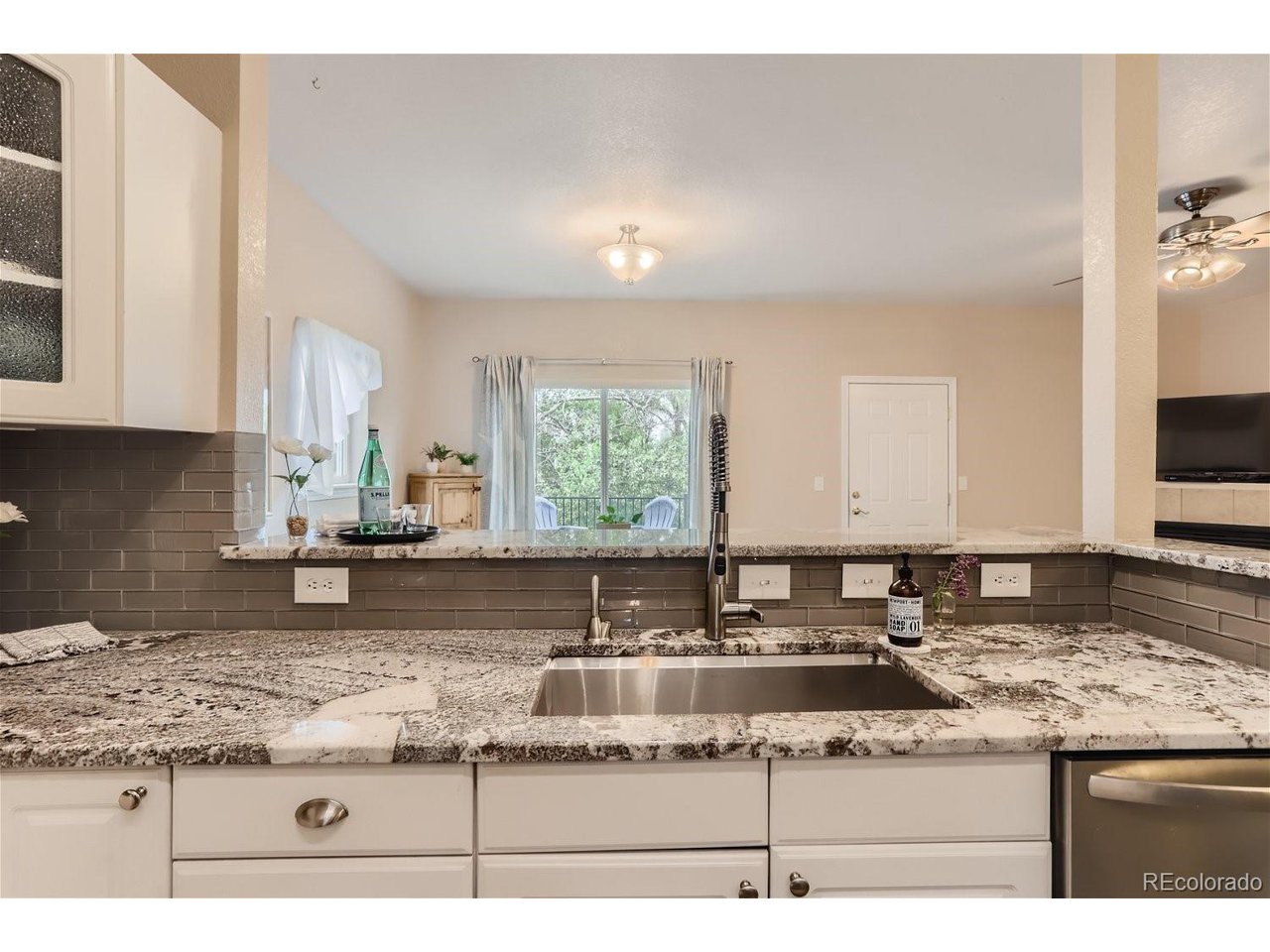 Kitchen with granite counters, gray tile backsplash, white cabinets, and a sink peninsula.
