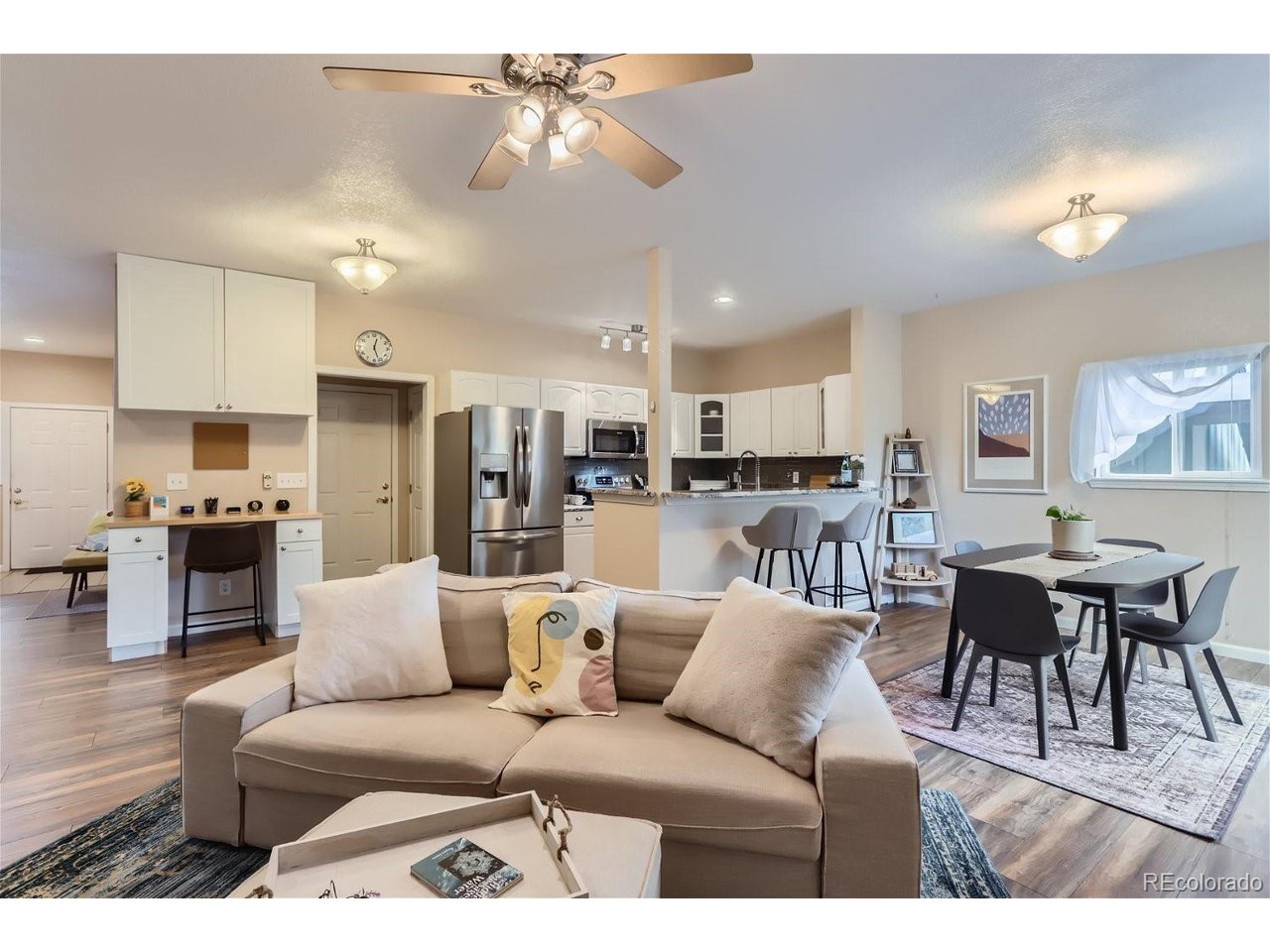 Open-plan living room, dining area, and kitchen with a beige sofa and breakfast bar.