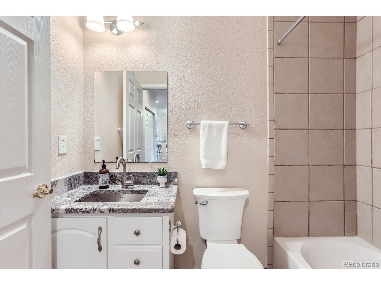 Bathroom with granite vanity and tiled tub surround.