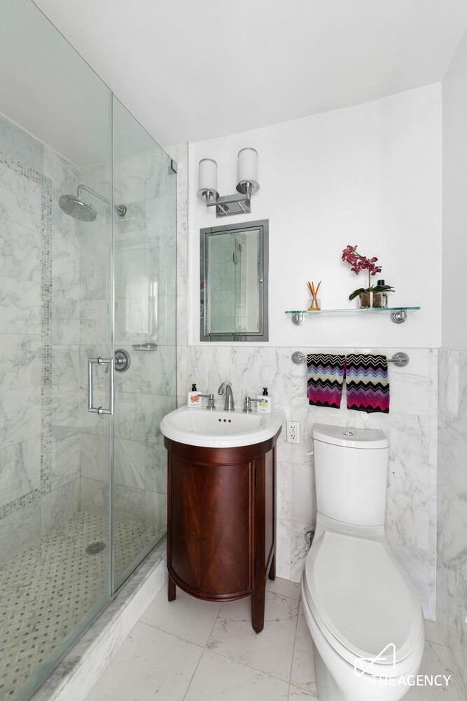 Bathroom with a glass-enclosed marble shower and dark wood vanity.