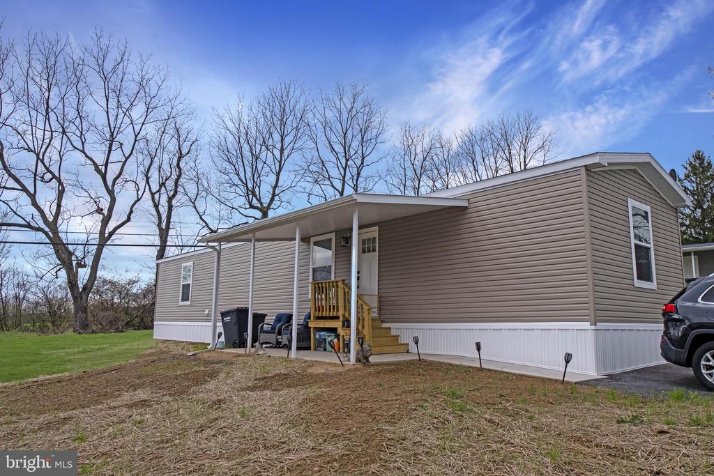 Single-story manufactured home with taupe siding, a covered porch, and wooden steps.