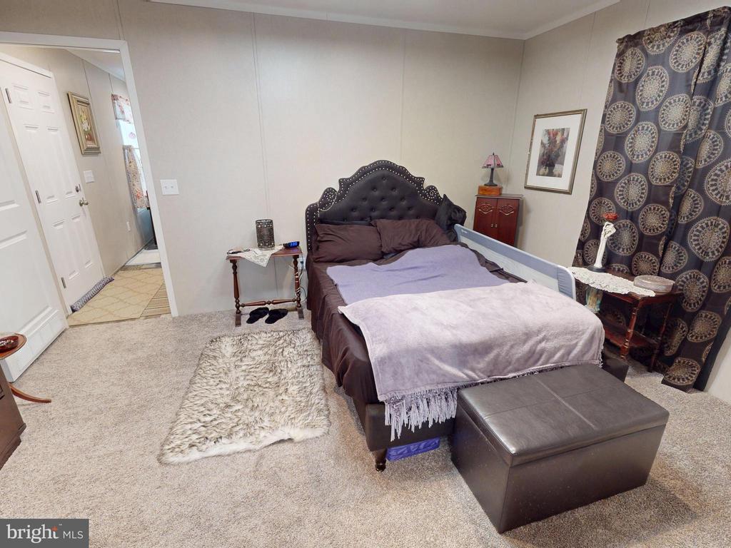Bedroom with a dark tufted headboard, purple bedding, and patterned curtains.