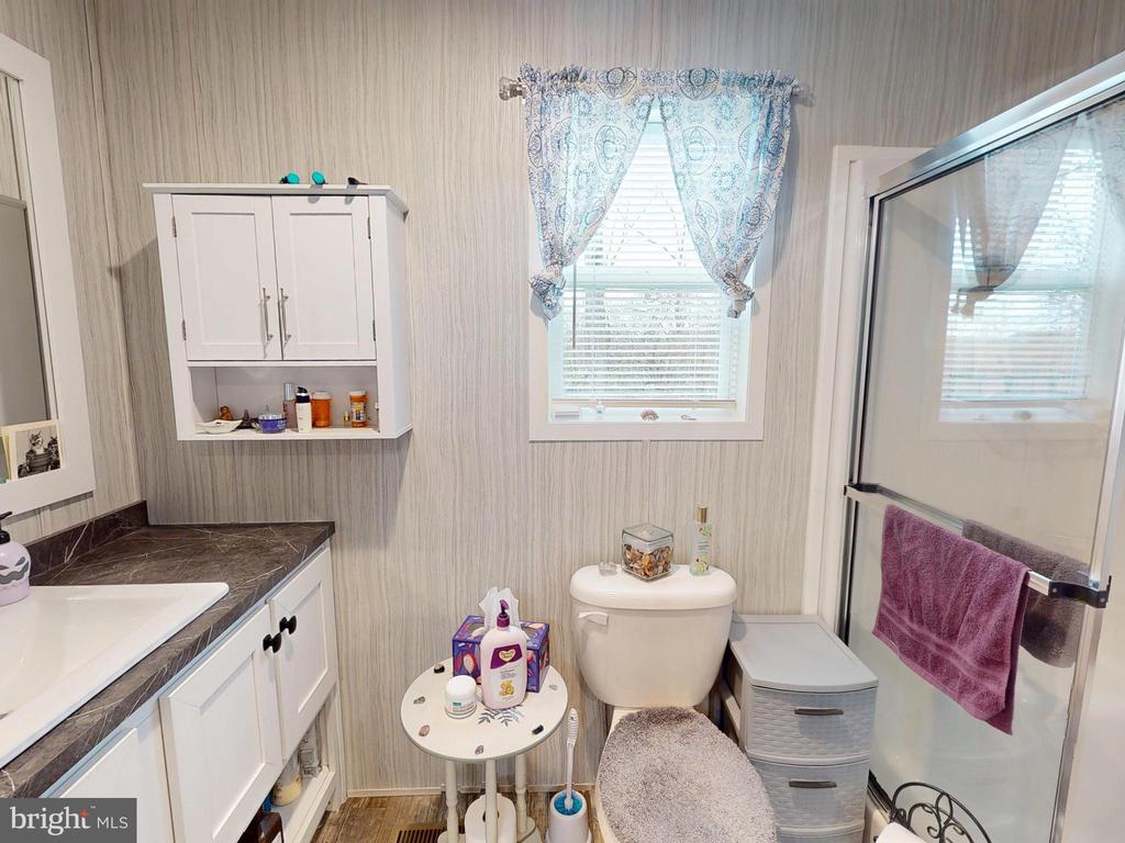 Bathroom with white vanity, wall cabinet, toilet, and glass-enclosed shower.