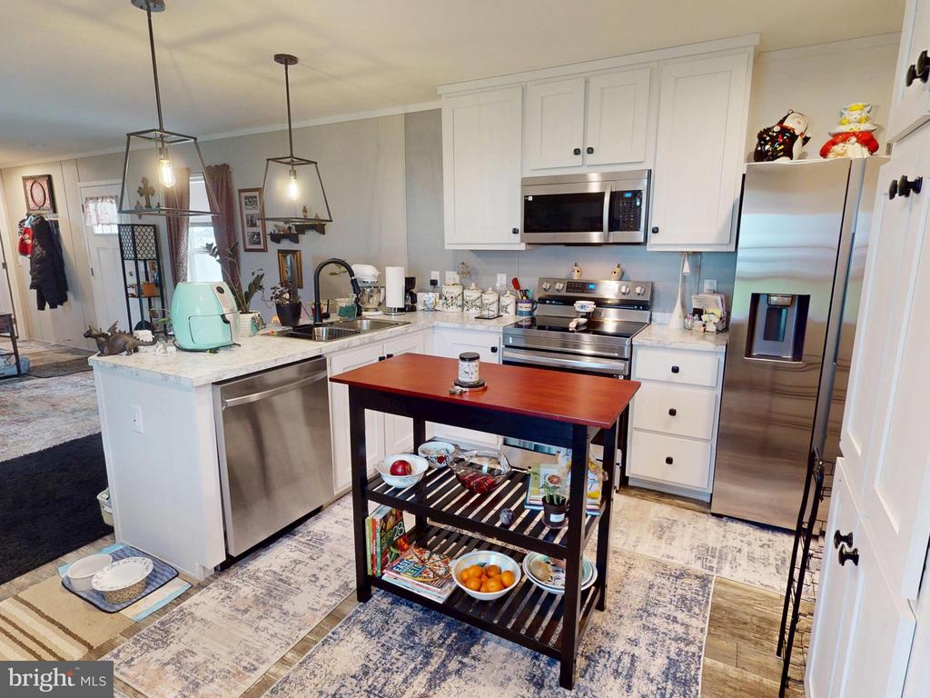 Kitchen with white cabinetry, stainless steel appliances, and a rolling island cart.