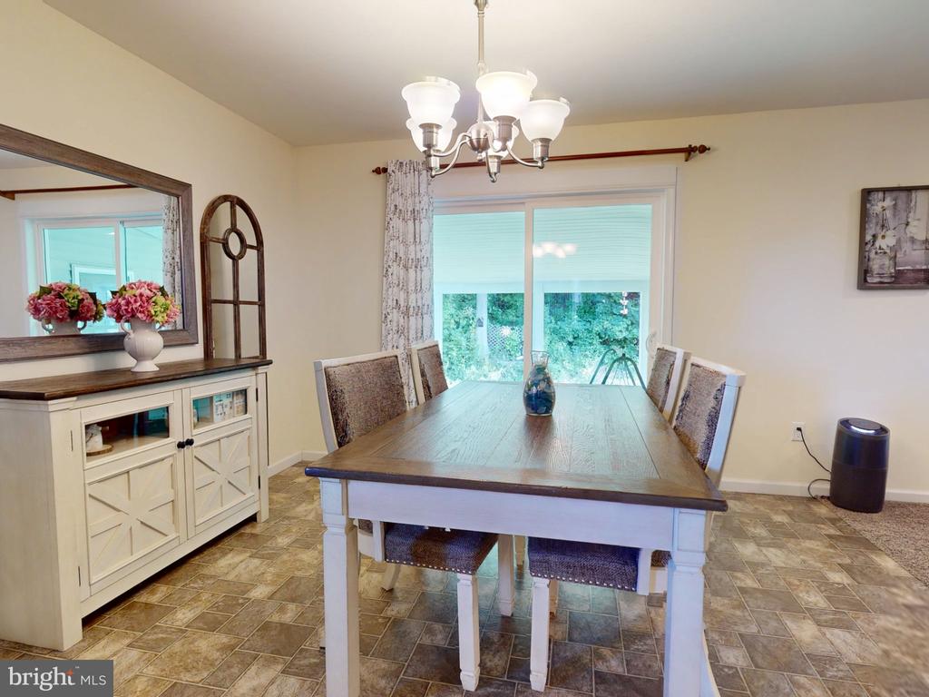 Dining room with a long wood-top table, upholstered chairs, and sliding glass doors.