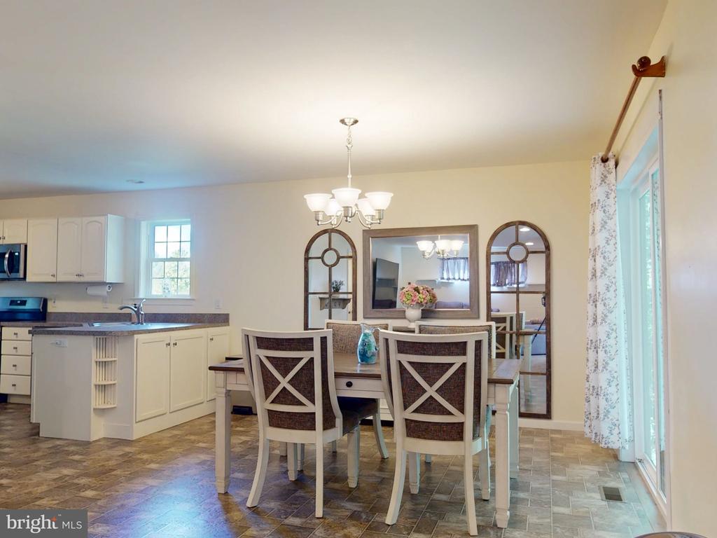 Open dining area with a white kitchen island, cross-back chairs, and tall glass doors.