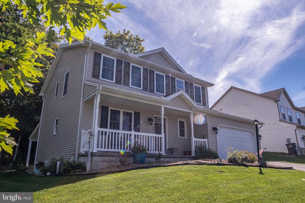 Two-story house with a covered front porch and attached garage, viewed from the front lawn.