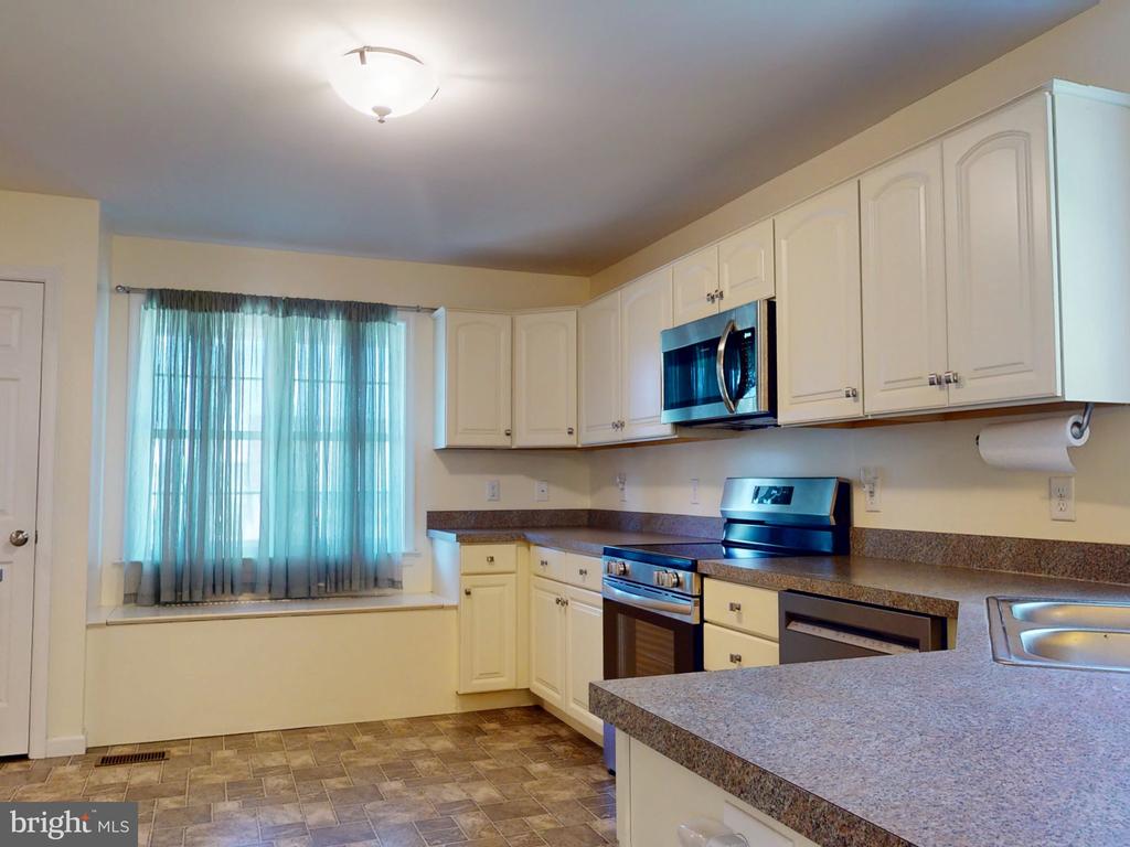 Kitchen with cream cabinets, granite countertops, and stainless steel appliances.