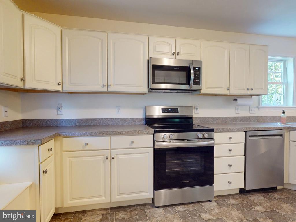 Kitchen with white cabinets, stainless steel appliances, and a window above the counter.
