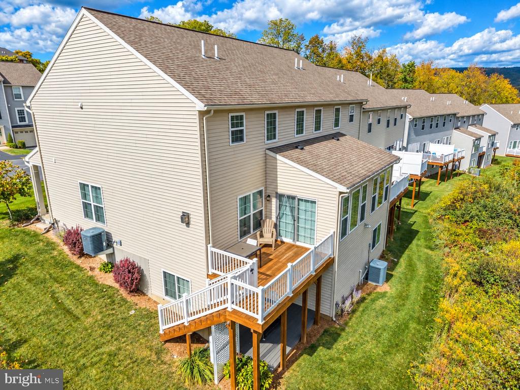 Townhouse rear with a raised wooden deck, white railings, and lawn.