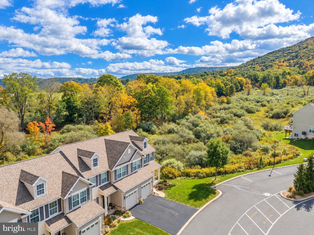 Aerial view of attached homes beside autumn-colored hills and landscaped grounds.