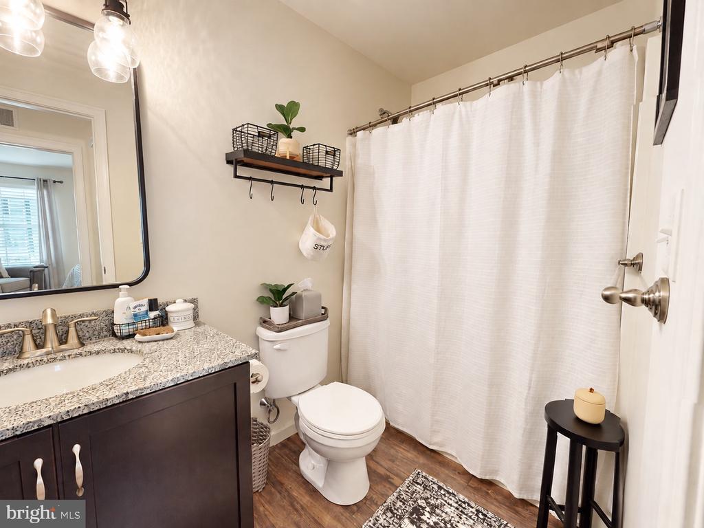Bathroom with dark wood vanity, patterned countertop, white toilet, and white shower curtain.
