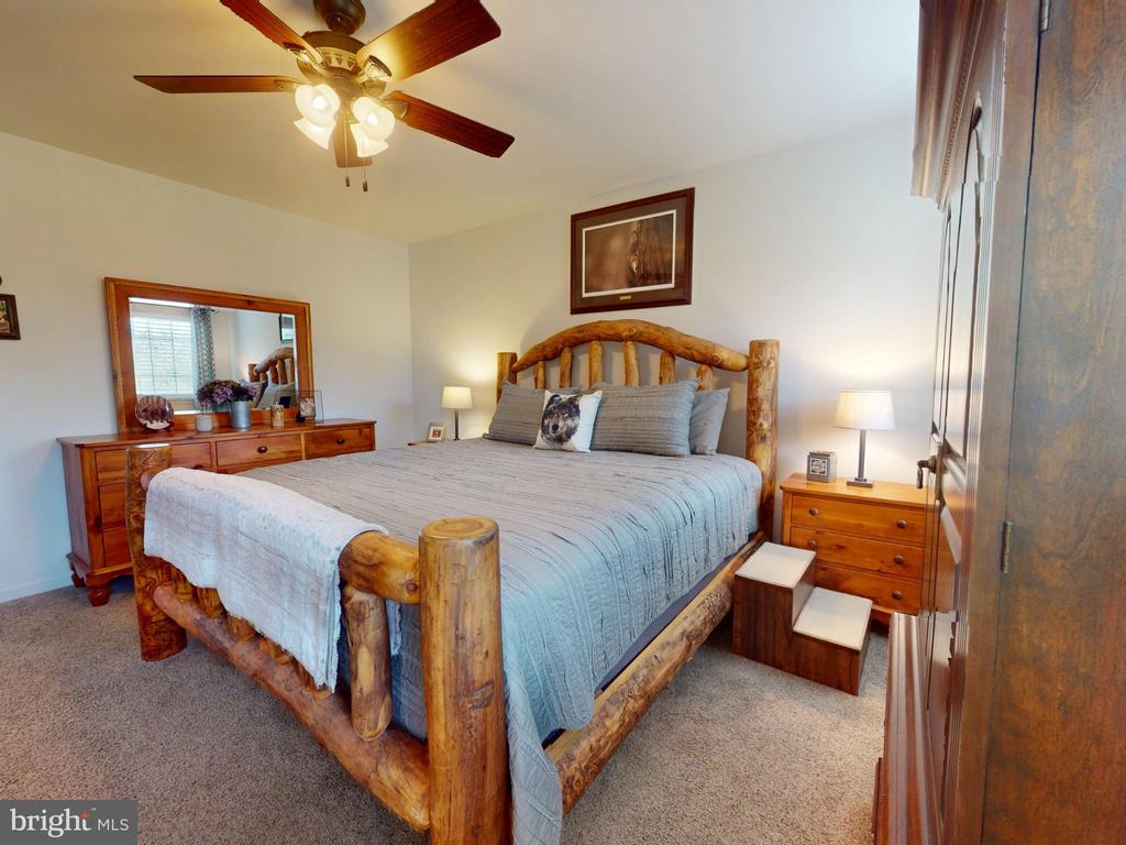 Bedroom with a rustic log bed, pale blue bedding, and matching wooden dresser and mirror.