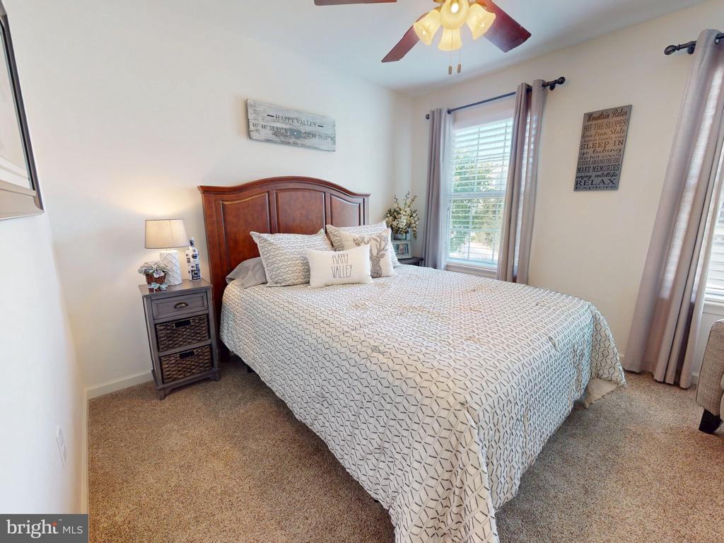 Staged bedroom with a large bed, curved wooden headboard, and tall curtained windows.
