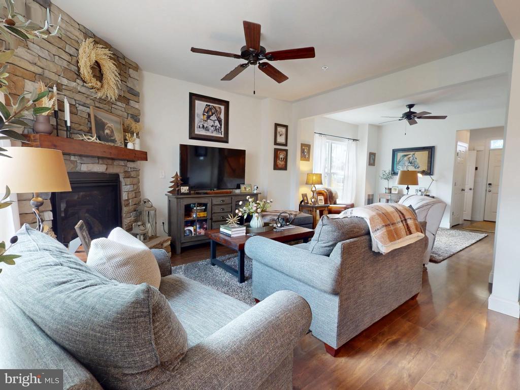 Living room with a stone fireplace, gray sofas, and hardwood floors.