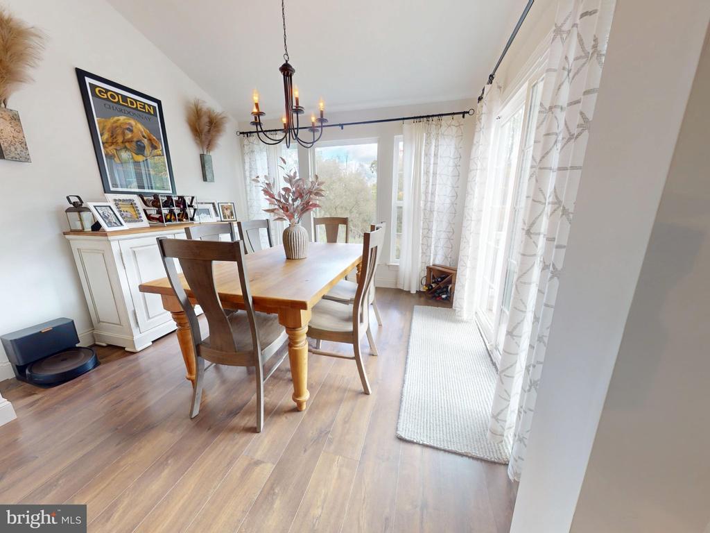 Dining room with a wooden table, white sideboard, chandelier, and tall windows.