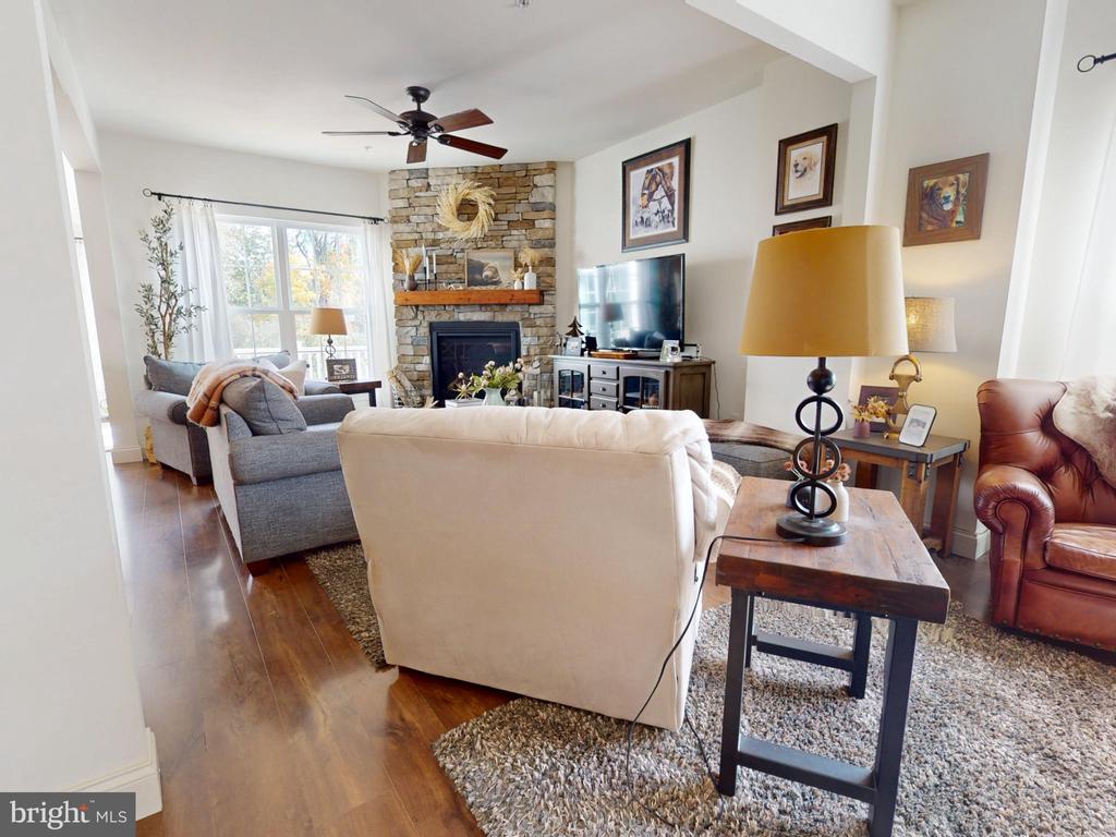 Living room with a stone fireplace, gray and cream sofas, and large windows.