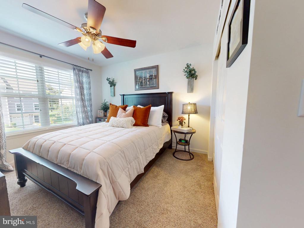 Furnished bedroom with a dark wood bed, rust-colored pillows, and wide windows with white blinds.