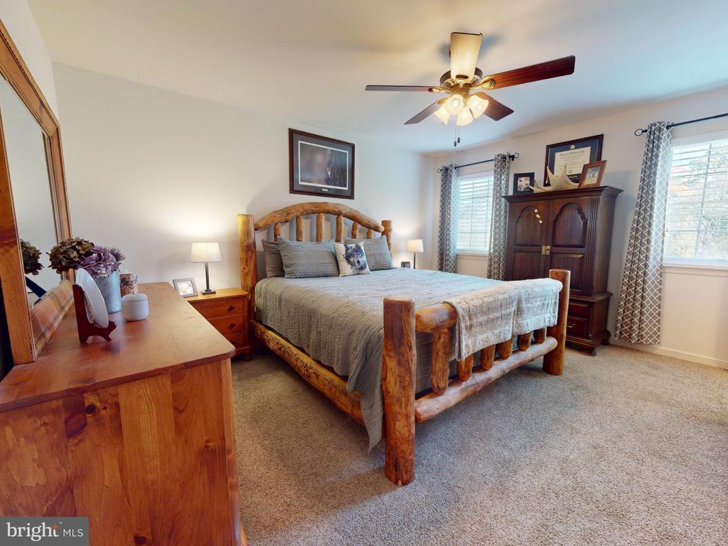 Bedroom with a rustic log bed, gray bedding, and a ceiling fan.