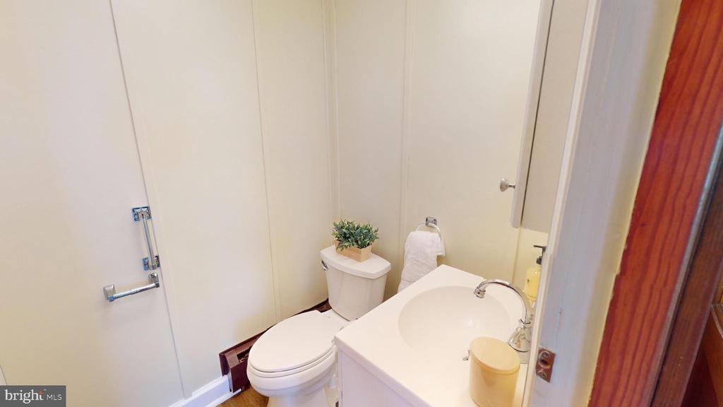 Compact bathroom with a white toilet and vanity sink.