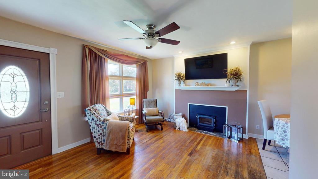 Living room with hardwood floors, a fireplace, and a curtained window.