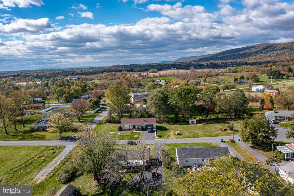 Aerial view of scattered homes and autumn trees across a valley, with wooded hills beyond.