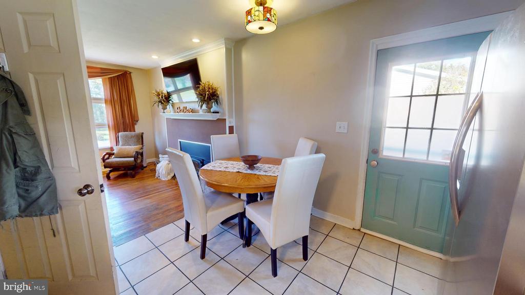 Dining area with a round wooden table beside a teal front door and adjoining living room.