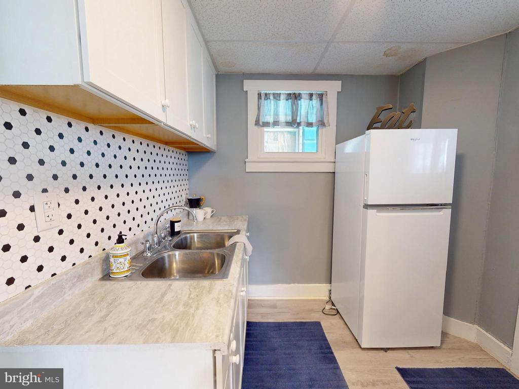 Kitchen with a hexagonal tile backsplash, double sink, and white refrigerator.