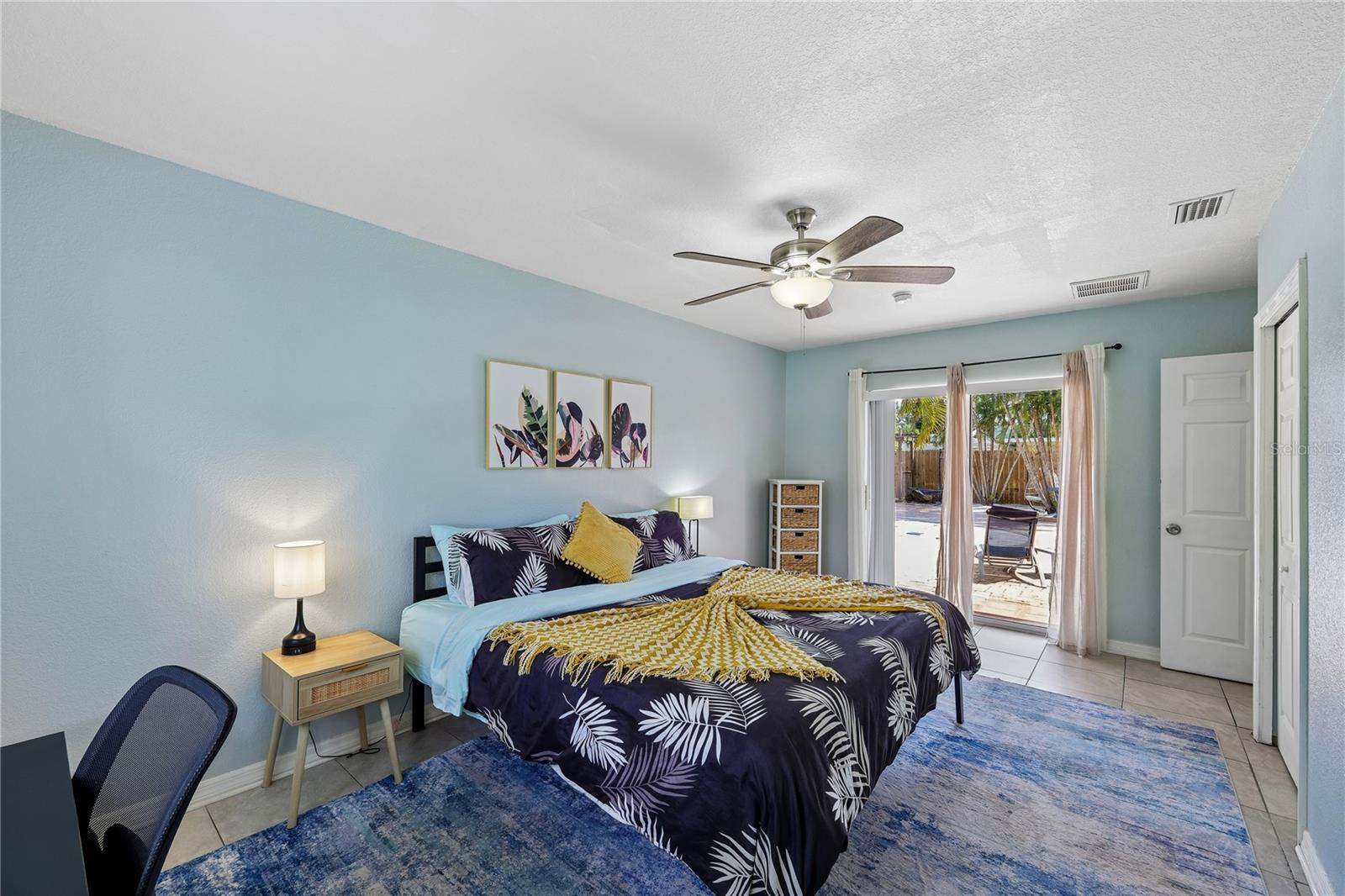 Furnished bedroom with navy botanical bedding and a sliding glass door to the patio.