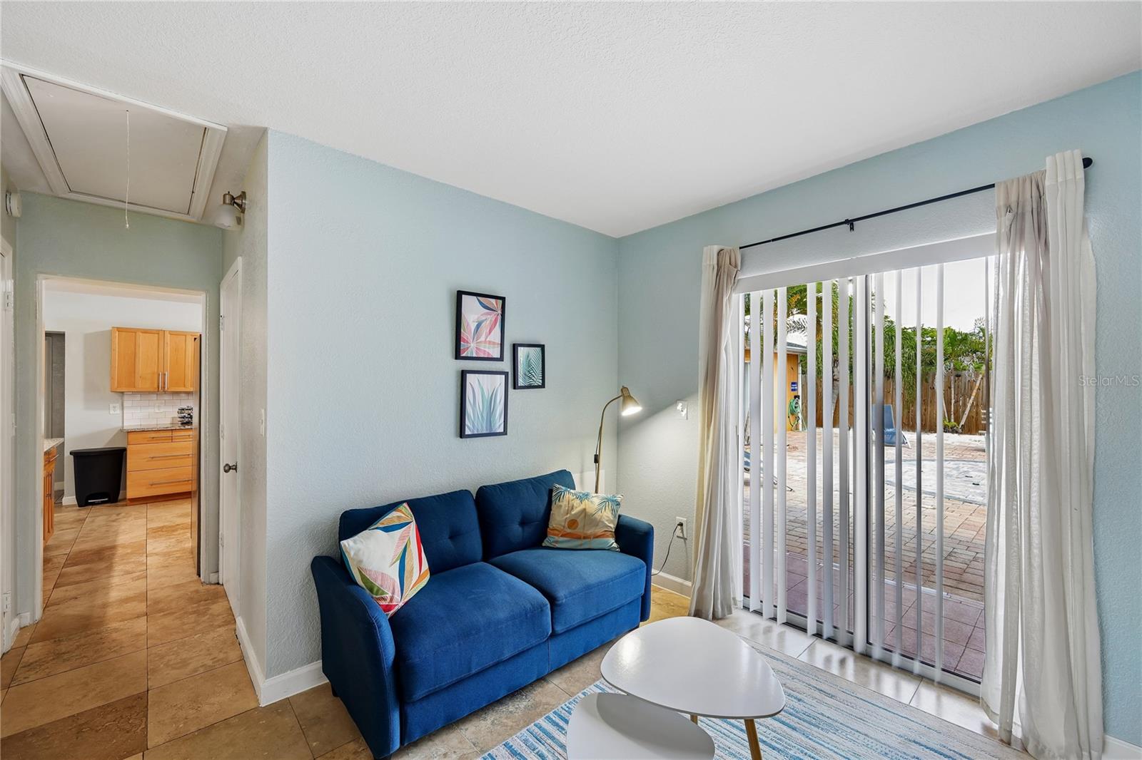 Living room with a blue sectional sofa and sliding glass doors opening to a paved patio.