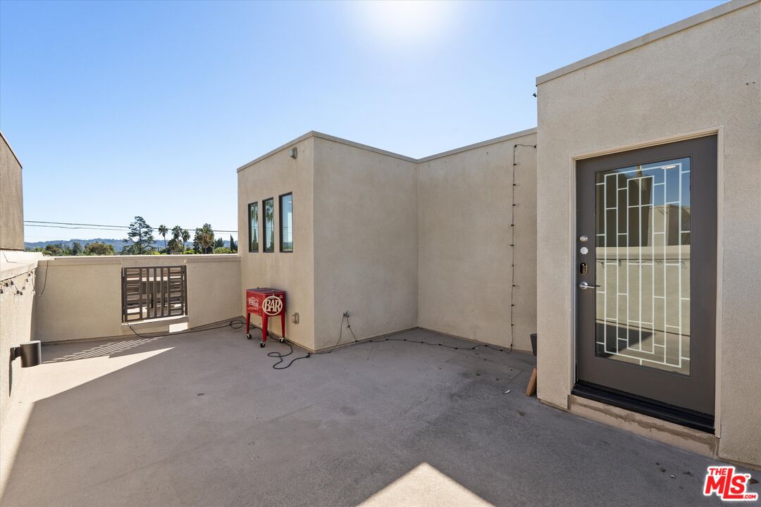 Rooftop terrace with a concrete patio, gated railing, and red Coca-Cola bar cart.
