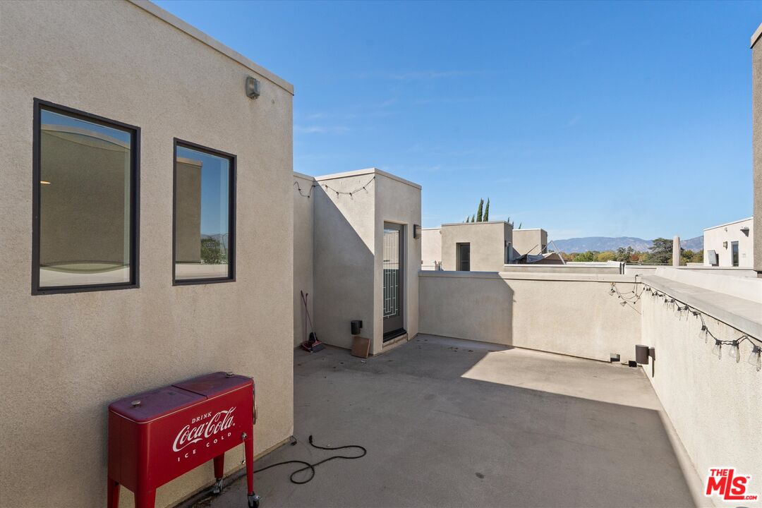 Rooftop terrace with a concrete deck, stucco walls, string lights, and distant mountain views.