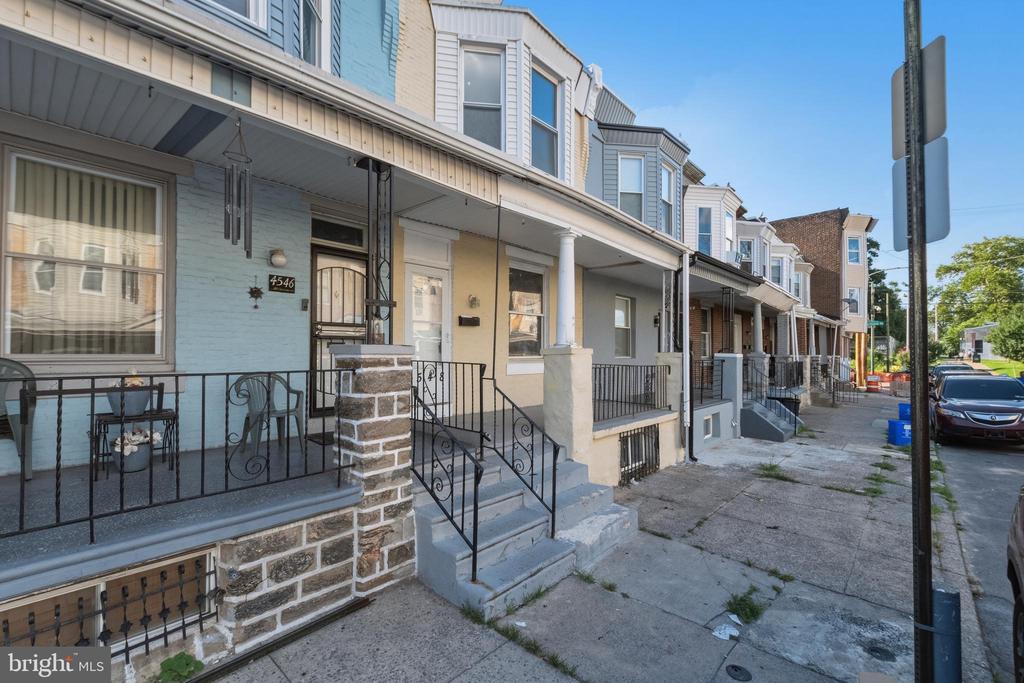 Attached Philadelphia rowhomes with covered porches, iron railings, stone walls, and concrete steps.