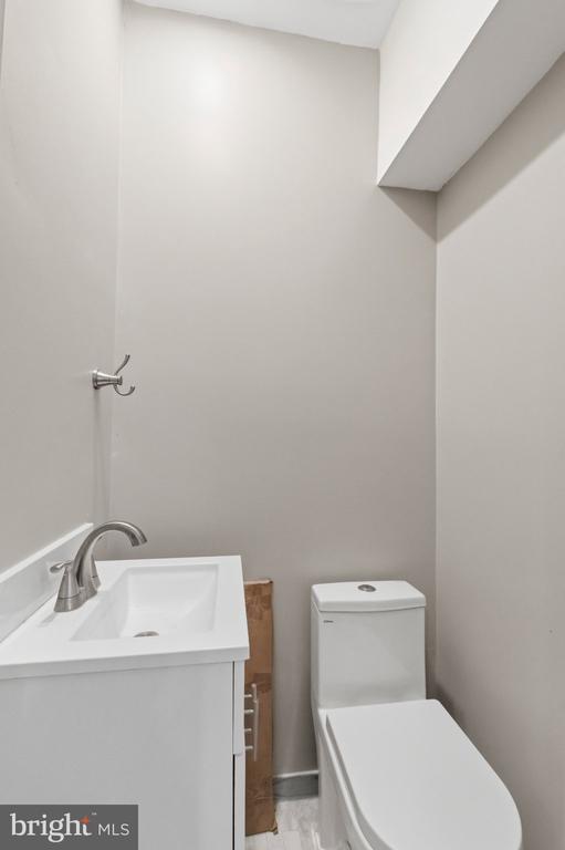 Bathroom with a white vanity and toilet beneath an angled soffit.