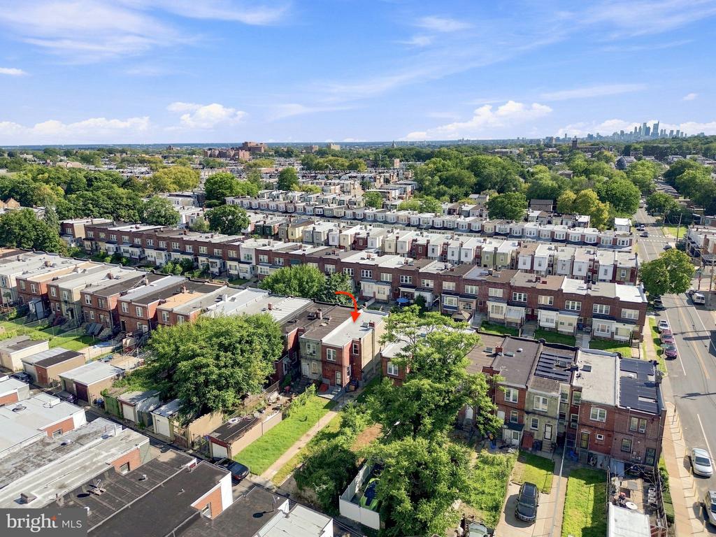 Aerial view of Philadelphia row houses, with an arrow marking one home and the skyline in the distance.