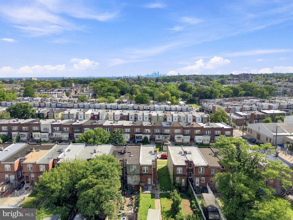 Aerial view of Philadelphia row houses, leafy blocks, and the distant city skyline.