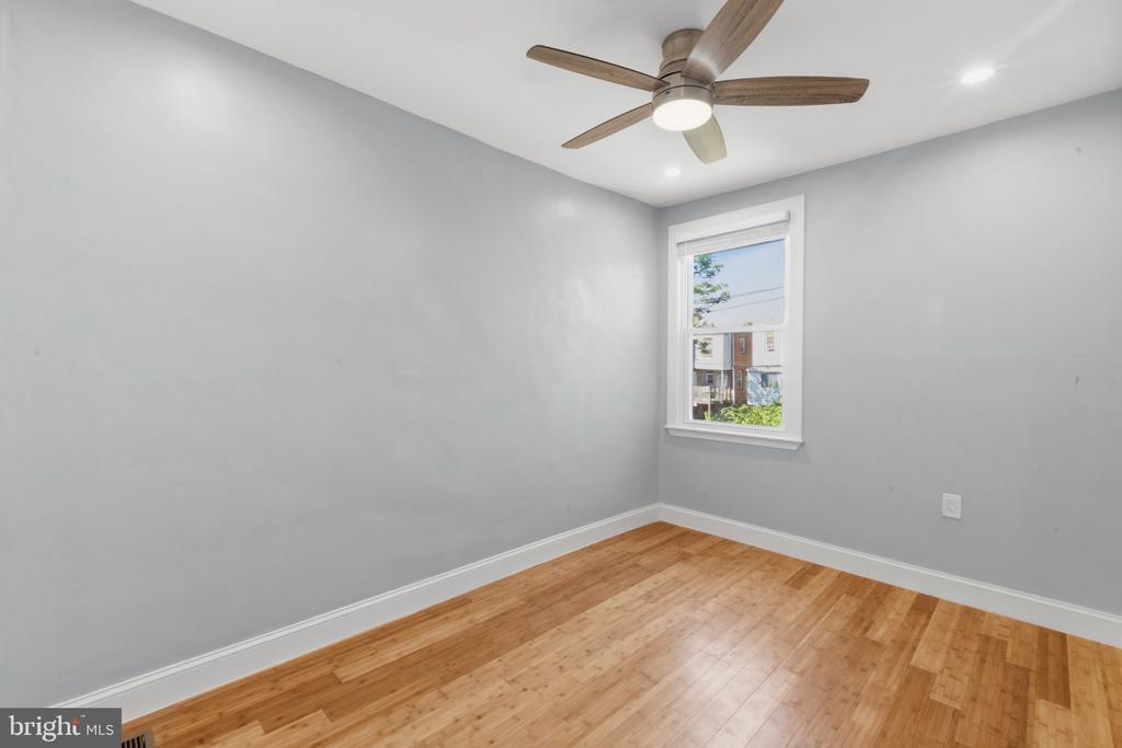 Empty room with hardwood floors, gray walls, and a ceiling fan.