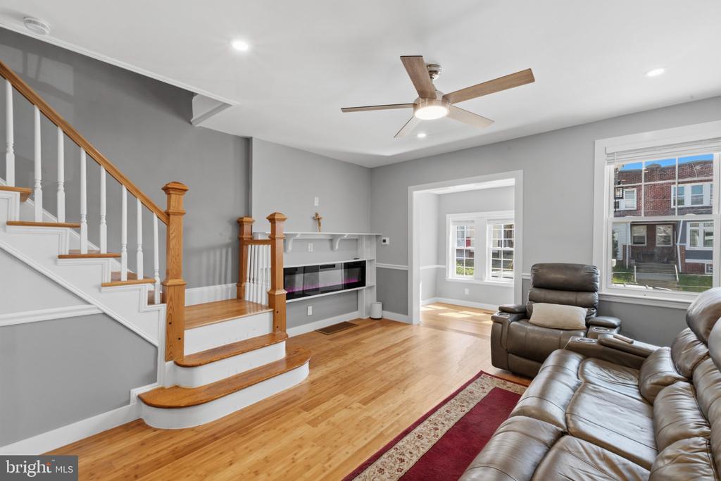 Living room with a wood-and-white staircase, built-in fireplace, hardwood floors, and leather recliners.