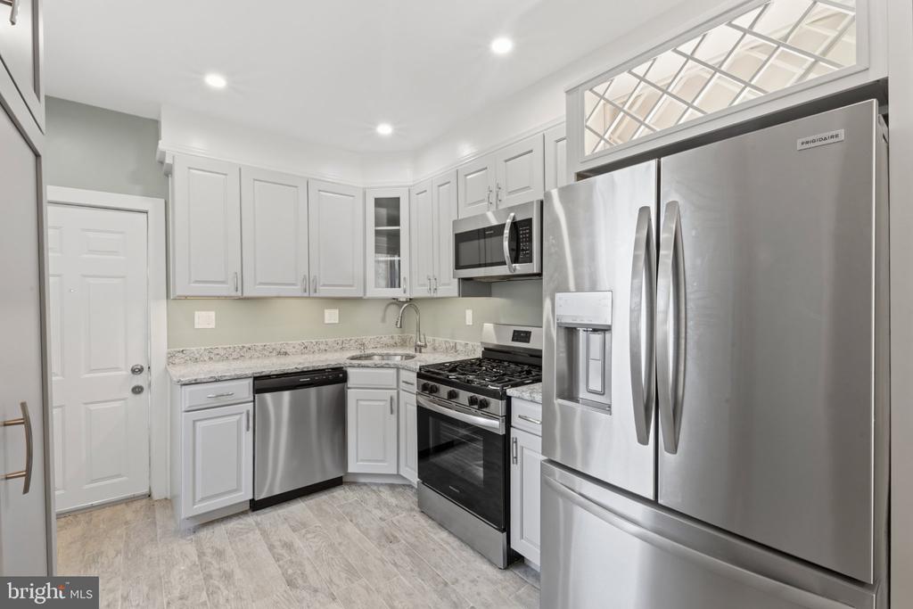 Kitchen with white shaker cabinets, stone countertops, and stainless steel appliances.